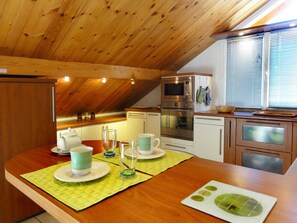 A kitchen with wooden ceiling beams, a built-in oven, and a window with blinds. - Beautiful 67m² apartment, 2 bedrooms, parking, south-facing balcony - Briançon (Briançon)
