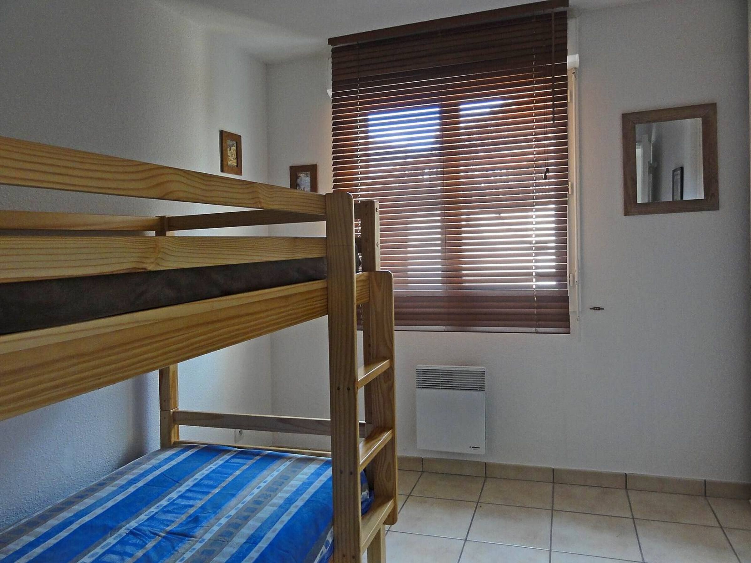 A bunk bed room with a window, a mirror, and a wall-mounted heater.