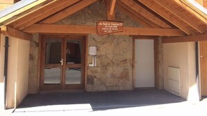 A wooden building with a stone facade, a wooden entrance, and a sign warning of ice on the roof. - Beautiful 67m² apartment, 2 bedrooms, parking, south-facing balcony - Briançon (Briançon)