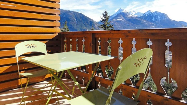 A wooden deck with a table and chairs, overlooking a mountainous landscape. - Beautiful 67m² apartment, 2 bedrooms, parking, south-facing balcony - Briançon (Briançon)