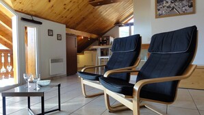 A cozy room with two reclining chairs, a small table with glasses, and a view of a village through a window. - Beautiful 67m² apartment, 2 bedrooms, parking, south-facing balcony - Briançon (Briançon)