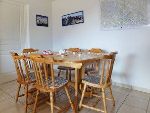 A dining area with a wooden table and chairs, a whiteboard with a map, and a door. - Beautiful 67m² apartment, 2 bedrooms, parking, south-facing balcony - Briançon (Briançon)