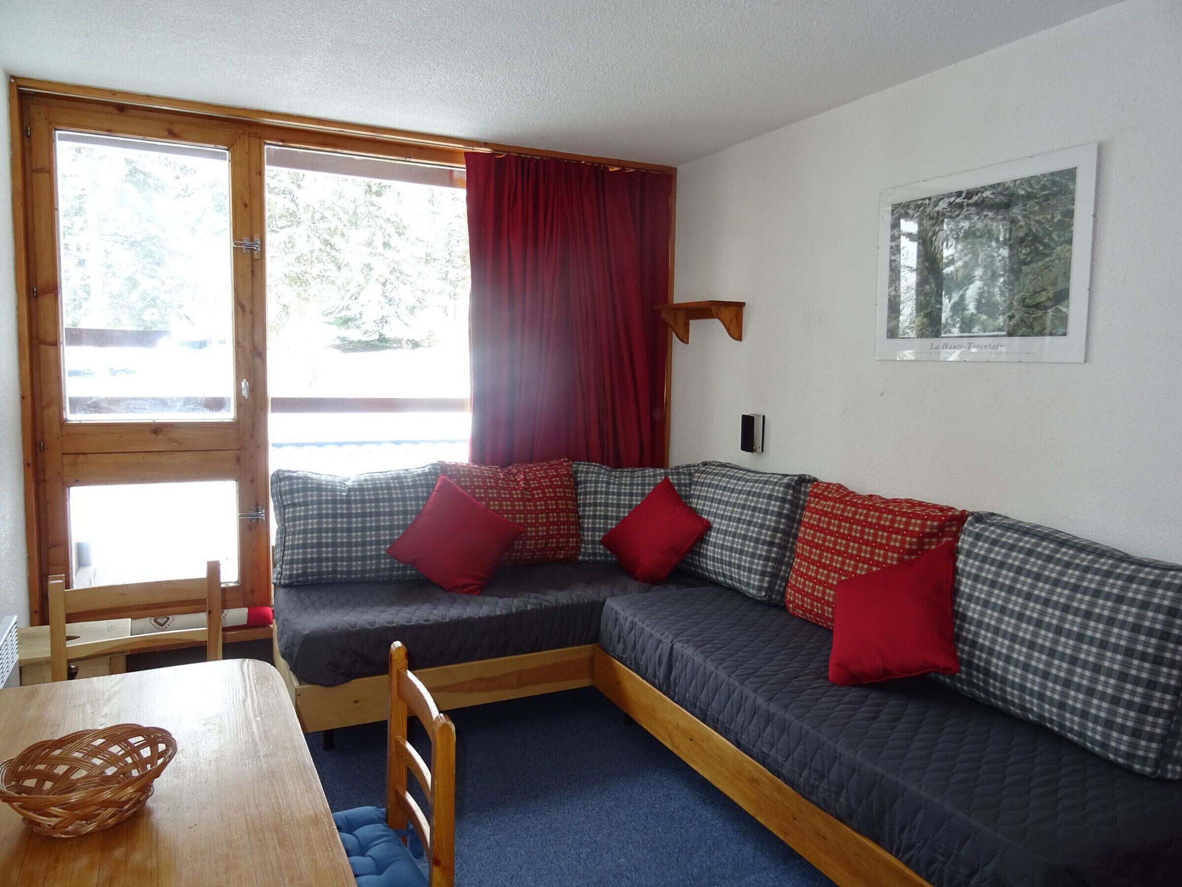 A cozy room with a sofa bed, a wooden table, and a basket.