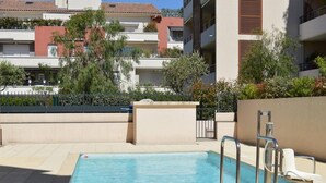 Ein rechteckiger Pool mit einer Metallleiter und einer weißen Liege.