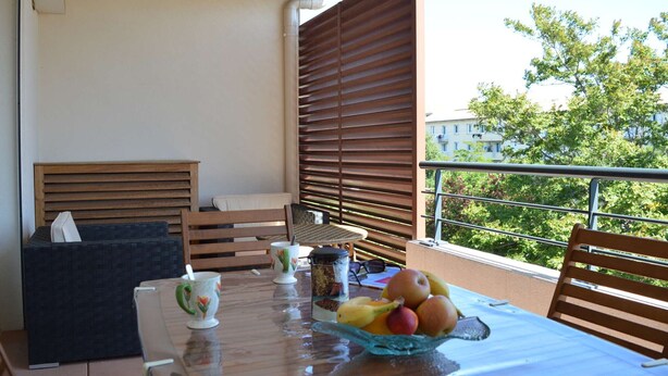 Ein Balkon mit einem Frühstückstisch, mit Obstschale, Tassen und einer kleinen Statue.