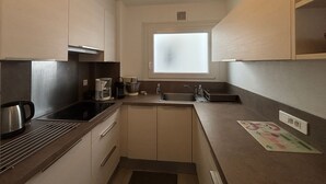 Una cocina compacta con estufa, lavamanos y ventana.
