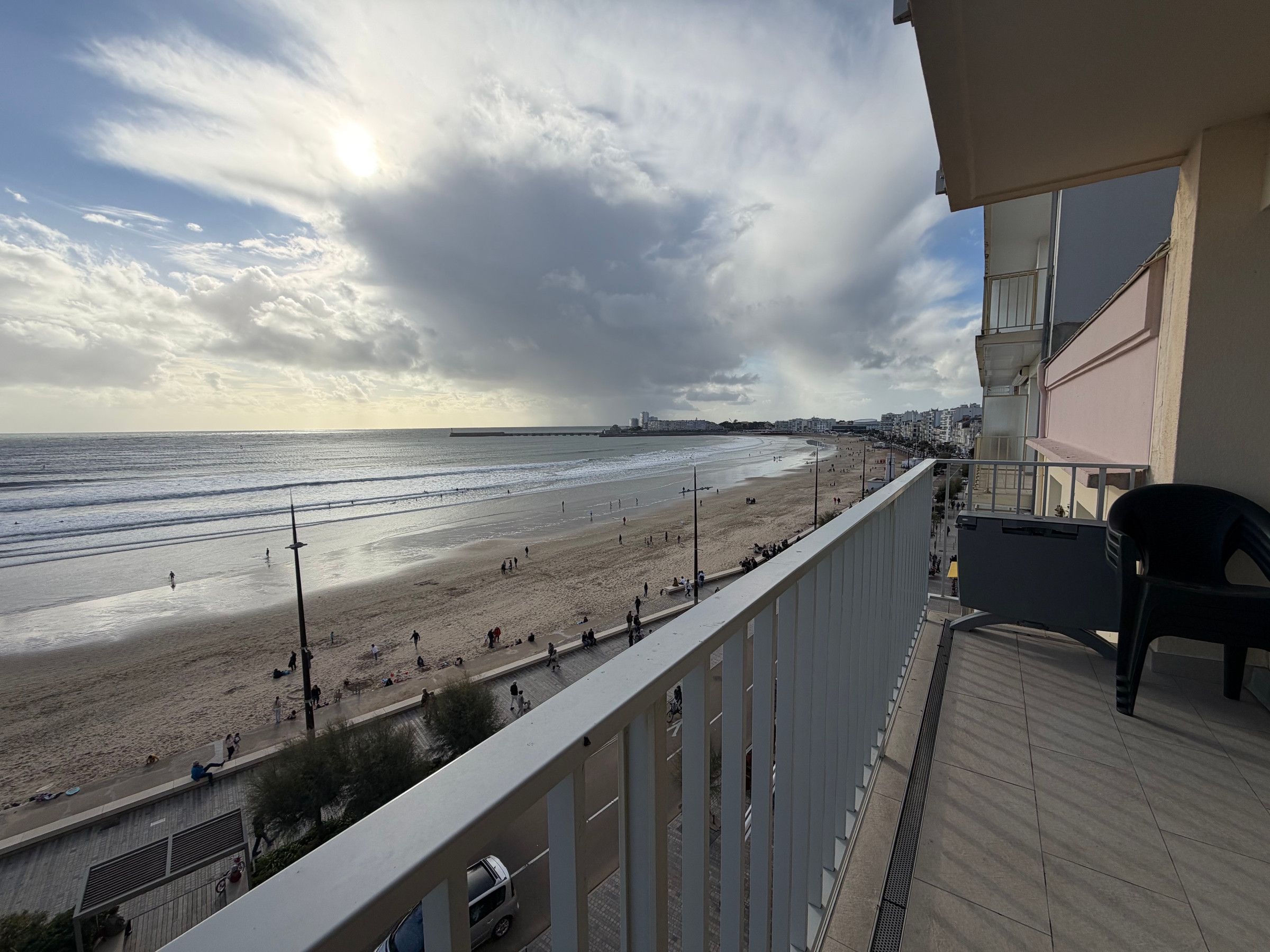 A balcony with a view of a beach and a distant cityscape.
