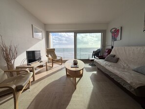 Un salon moderne avec un canapé, des fauteuils, une table basse et un téléviseur.