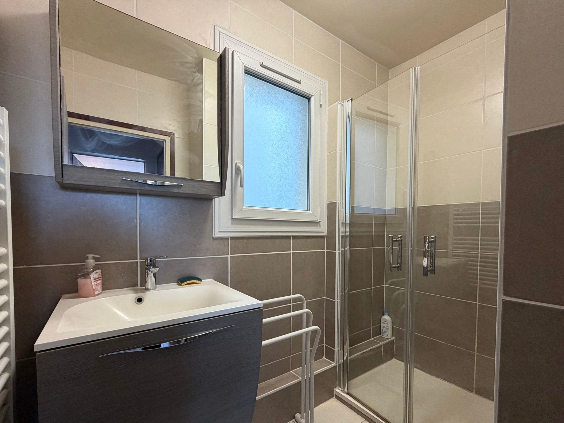 A bathroom with a sink, mirror, and shower.