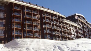 A multi-story hotel with balconies and a snow-covered ground.