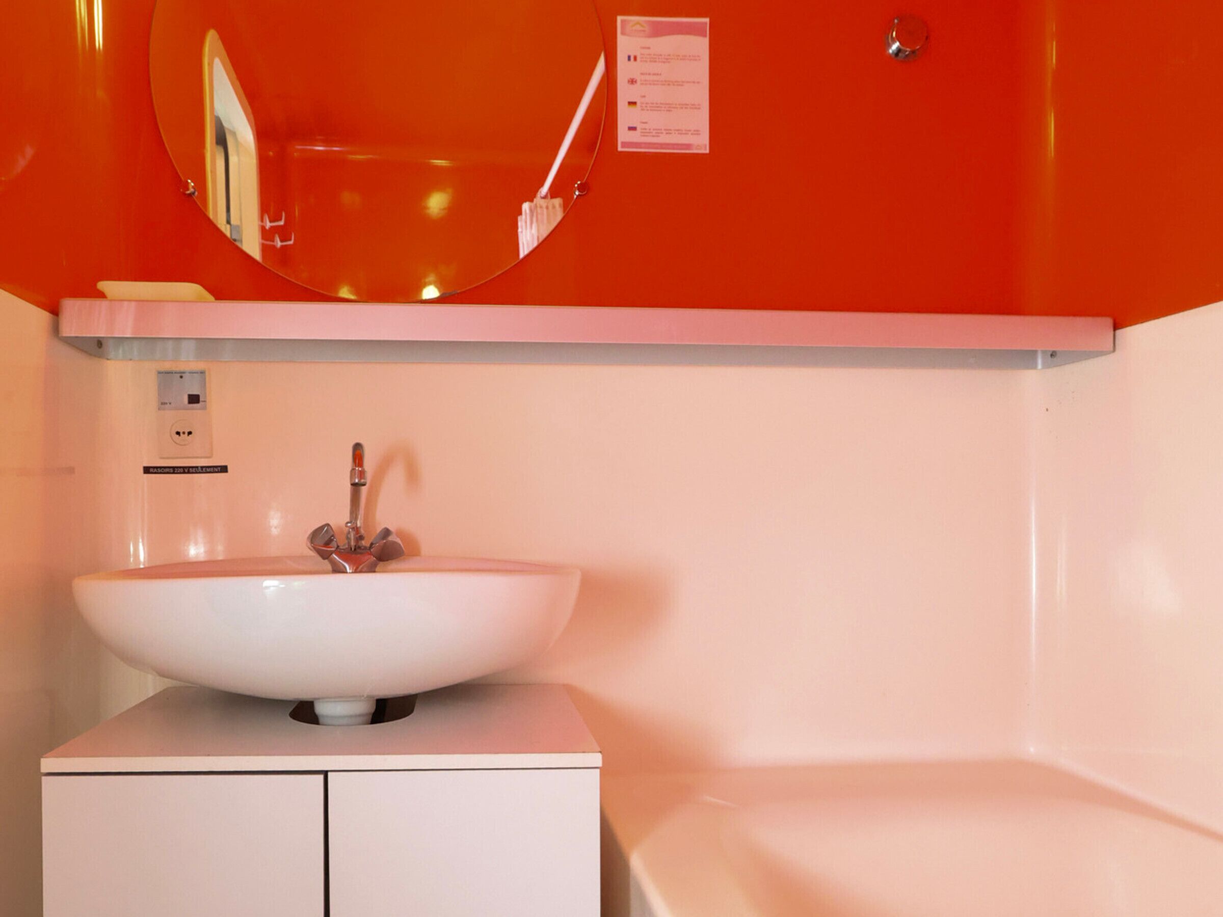 A bathroom with a white sink, a mirror, and a red wall.