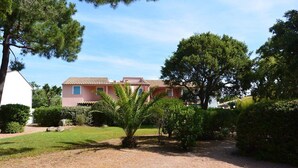 A two-story building with a tiled roof, surrounded by a well-maintained garden with various shrubs and a palm tree. - MINI-VILLA SAINT CYPRIEN C20- 3***-QUIET (Saint-Cyprien Lecci)