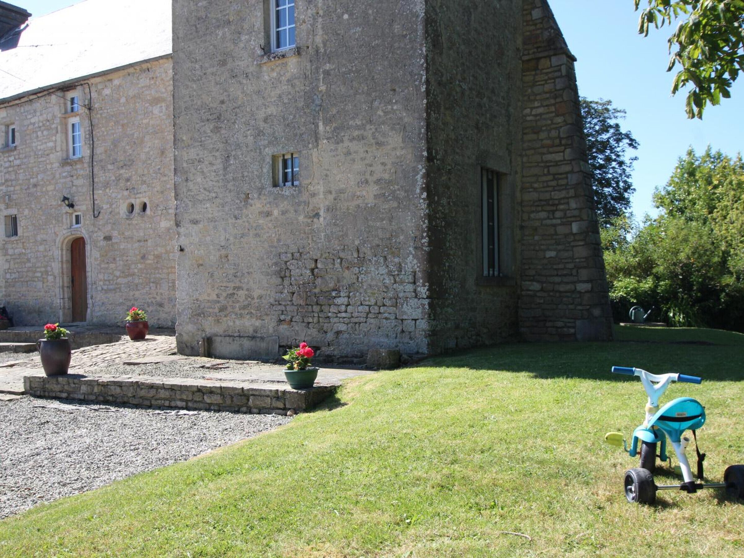 Un edificio de piedra con un patio empedrado y plantas en macetas.