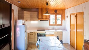 Eine kleine Küche mit Holzausstattung, integriertem Backofen, Spüle und einem Essbereich mit Tisch.
