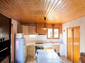 A compact kitchen with wooden cabinets, a built-in oven, a sink, and a dining area with a table.