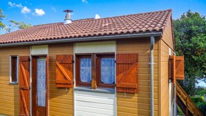Ein Holzhaus mit Ziegeldach, Schornstein und einer kleinen Veranda mit einer Holztreppe.