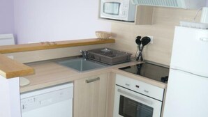 A compact kitchen with a dishwasher, oven, microwave, and a small sink.