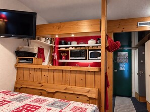 A compact room with a bed, a television, a kitchenette with a microwave, and a door with a poster. - 2-room Apartment for 6, balcony & Wifi in Arcs 1800 (Les Arcs 1800)