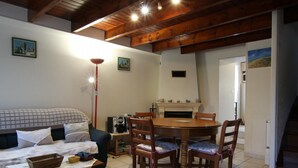 Una habitación acogedora con una cama, una mesa de comedor con sillas, una chimenea y una escalera.