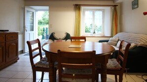 Una habitación acogedora con una mesa de madera, sillas, un sofá y una ventana con cortinas.