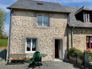 Ein Steinhaus mit einer zweistöckigen Struktur, einer Haustür und einem kleinen Vorbereich.