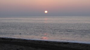 Una playa al atardecer con aguas tranquilas y cielo despejado.