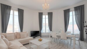 Ein modernes Wohnzimmer mit einer Couch, einem Couchtisch, einem Fernseher und einem Essbereich mit Stühlen und einem Tisch.