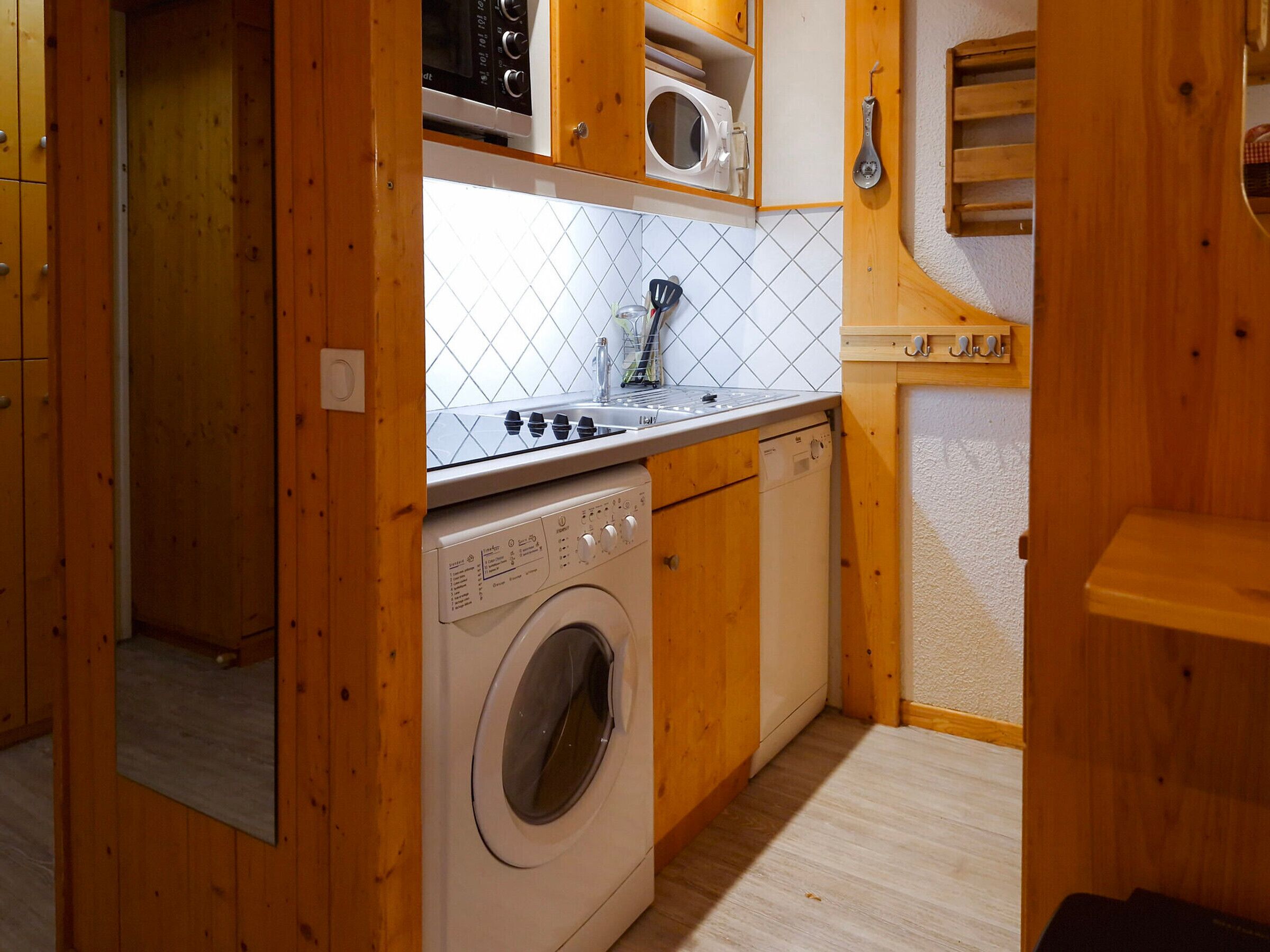 A compact kitchen with a washing machine, microwave, and stove.