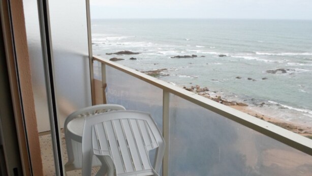 A balcony with a view of the ocean, a white plastic chair, and a tiled floor. - 2-Bedroom Apartment with Balcony and Garage in Les Sables-d'Olonne (Les Sables-d'Olonne)
