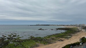 A coastal cityscape with a sandy beach, rocky shoreline, and buildings in the distance. - 2-Bedroom Apartment with Balcony and Garage in Les Sables-d'Olonne (Les Sables-d'Olonne)