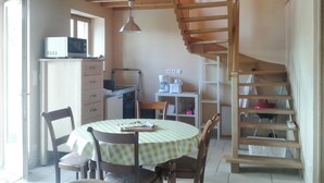 Una cocina acogedora con comedor, una escalera de madera y un microondas en la encimera.