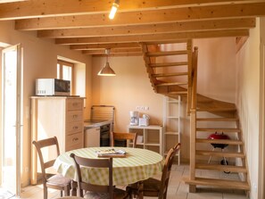 Una cocina acogedora con una mesa de comedor, sillas, un microondas y una escalera de madera.