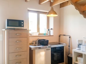 Una cocina compacta con microondas, pileta y estufa.
