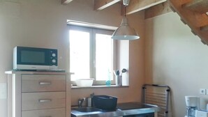 Una cocina compacta con microondas, un lavamanos y un horno pequeño.