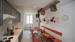 A kitchen with a stove, sink, and dining area with red checkered tables and chairs. - grimm 160m2 city center 3br 3bth (Colmar)