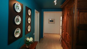 A hallway with blue walls, a wooden cabinet, and a door with a framed picture. - grimm 160m2 city center 3br 3bth (Colmar)
