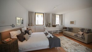 A bedroom with a bed, a sofa, a desk, and a window with curtains. - grimm 160m2 city center 3br 3bth (Colmar)