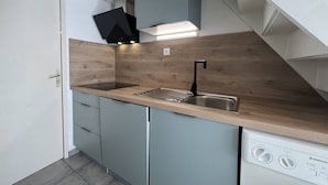 Una cocina compacta con lavavajillas integrado, un lavamanos con grifo moderno y un protector de pared de madera.
