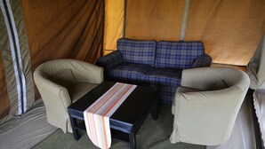 A tent interior with a sofa, two armchairs, and a table.