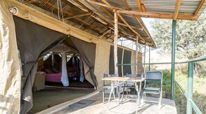 A tented accommodation with a bed, a table, and two chairs. - Serengeti Ikoma Wild Camp (Serengeti)