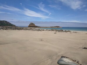 A wide sandy beach with scattered rocks and a prominent rock formation in the distance. - Homerez - Charming House in Guimaëc, Sea View (Guimaëc)