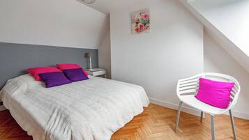 A bedroom with a bed, a chair, a nightstand, and a painting on the wall.