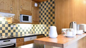 A kitchen with wooden cabinets, a microwave, a Bosch dishwasher, and a checkered backsplash. - 3-room apartment with balcony and WIFI, 150m from slopes, 6 people - Méribel (Méribel)