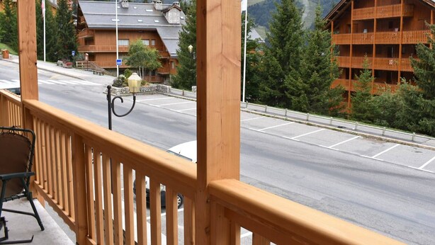 A wooden balcony with a view of a road, a mountain, and a building with a balcony. - 3-room apartment with balcony and WIFI, 150m from slopes, 6 people - Méribel (Méribel)