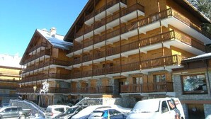 A multi-story wooden building with balconies, likely a hotel or lodge, with cars parked in front. - 3-room apartment with balcony and WIFI, 150m from slopes, 6 people - Méribel (Méribel)