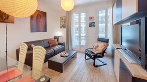A modern living room with a sofa, armchair, coffee table, and a flat-screen TV. - N&J - TROIS PROMENADE - Central - Very close sea (Niza)