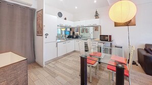 A modern kitchen with white cabinets, a glass dining table, and a large pendant light. - N&J - TROIS PROMENADE - Central - Very close sea (Niza)