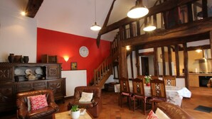 A cozy living room with leather sofas, a wooden coffee table, and a red accent wall. - Spacious Cottage in South Manche with Fireplace and Private Garden (Le Grand-Celland)