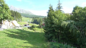 Paisaje rural con una montaña al fondo, un edificio pequeño y un camino para bicicletas.
