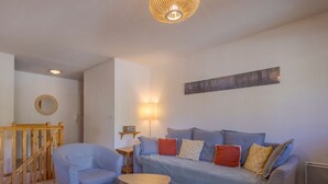 A living room with a sofa set, a coffee table, a wooden railing, and a wall-mounted lamp.